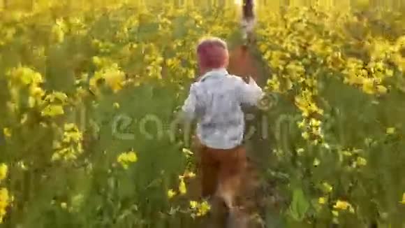 日落时女孩和男孩跑过田野视频的预览图