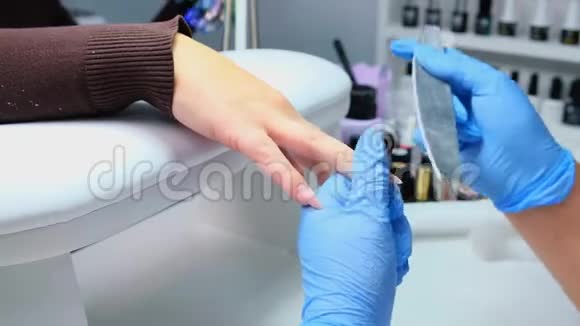 特写镜头一名妇女在美甲沙龙接受美容师用指甲锉修指甲修指甲的女人视频的预览图