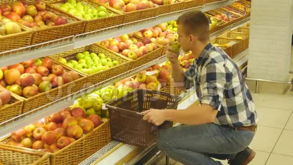 人们在杂货店挑选新鲜的红苹果然后把它放进篮子里帅哥就是视频的预览图