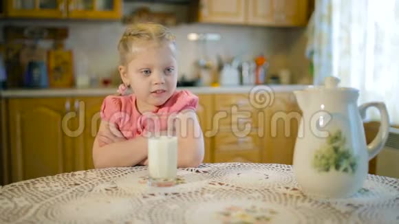 女孩端着一杯牛奶坐在桌子旁看电视视频的预览图