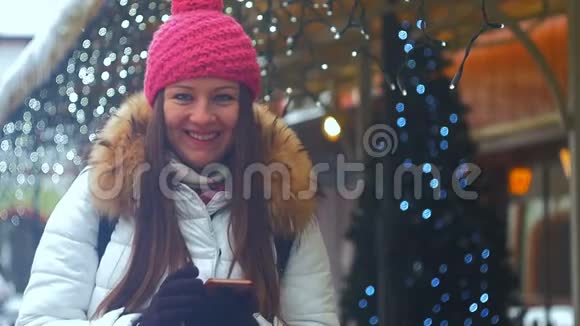 年轻女子微笑着面对冬天的城市使用电话视频的预览图