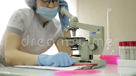 在实验室条件下使用显微镜和试管的女性医学研究人员在电话中交谈视频的预览图