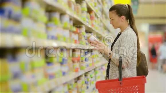 年轻的女人在超市里选择婴儿食品母亲在市场上为孩子选择食物女孩站在附近视频的预览图