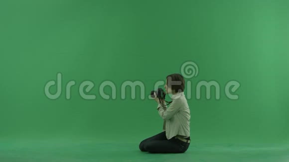 坐着的年轻女子正在绿色屏幕上左手边拍照视频的预览图