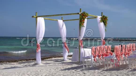 在热带海滩上装饰着鲜花和大型风力开发织物的婚礼拱门青绿色的水视频的预览图