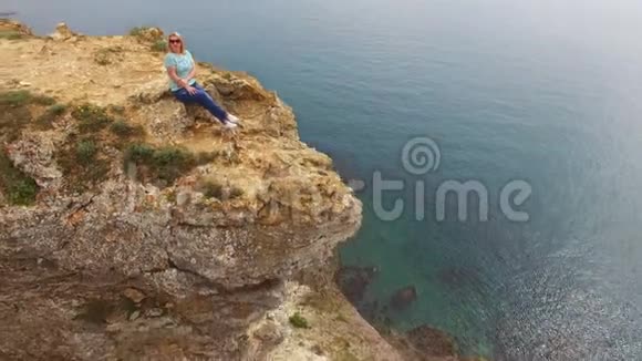 坐在海边岩石上的年轻女子视频的预览图
