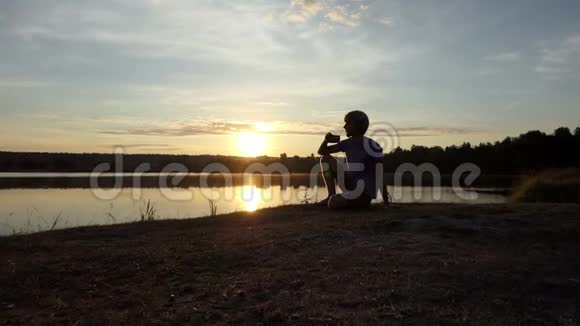 夕阳西下年轻人坐在湖边喝茶视频的预览图