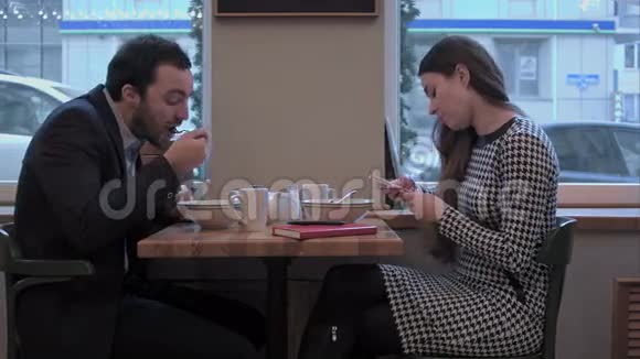 商人和女人在咖啡馆的午餐上用智能手机交流视频的预览图