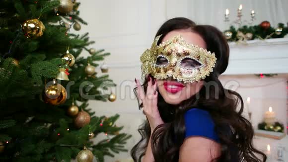美丽的女孩戴着面具庆祝新年圣诞化妆舞会圣诞树附近的派对一个年轻的女人穿着一件衣服视频的预览图