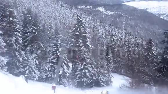 群山树木覆盖着雪一辆坐着滑雪者的缆车升起视频的预览图