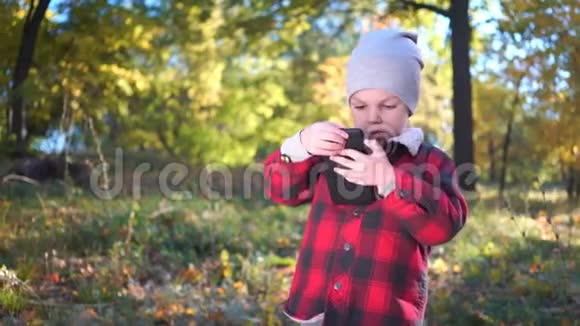 男孩正在秋天公园玩智能手机游戏视频的预览图
