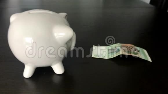 一个女人把500个俄罗斯卢布的钞票放进储蓄罐视频的预览图