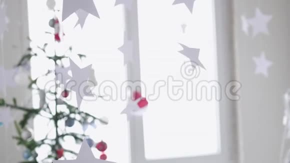 纸星星挂在窗户旁边的一棵圣诞树的背景上圣诞节的概念慢动作4k视频的预览图