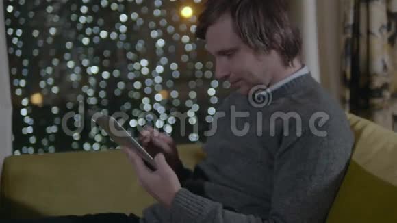 接近坐在咖啡馆里的男性浏览带有新年背景的平板电脑视频的预览图