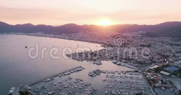 在马尔马里斯日落时可鸟瞰船只游艇和城市视频的预览图