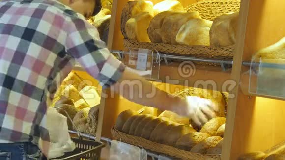 人们在超市里选择并把一个新鲜的面包放进一个包裹里年轻人拿着一块面包视频的预览图