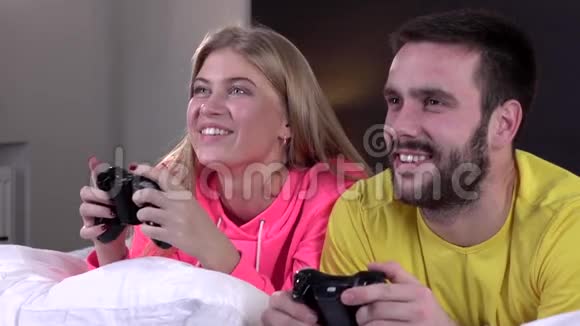 年轻夫妇穿着睡衣一起玩电子游戏慢动作特写视频的预览图