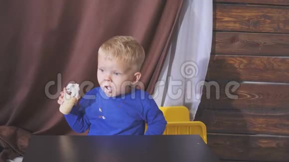 坐在高椅子上吃冰淇淋的男孩可爱的孩子在华夫饼锥里享受冰淇淋看着视频的预览图