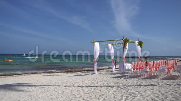 在热带海滩上装饰着鲜花和大型风力开发织物的婚礼拱门青绿色的水视频的预览图