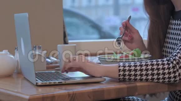 年轻女商人用手提电脑工作的武器她正坐在咖啡馆的桌子旁吃着沙拉视频的预览图