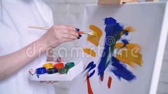 穿围裙的年轻女艺术家在艺术工作室画画布视频的预览图