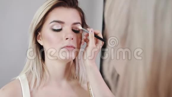 化妆年轻漂亮的女孩用刷子在脸颊上化妆视频的预览图