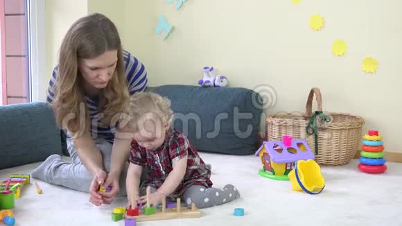 可爱的小女孩把五颜六色的木砖放进妈妈的手掌里视频的预览图