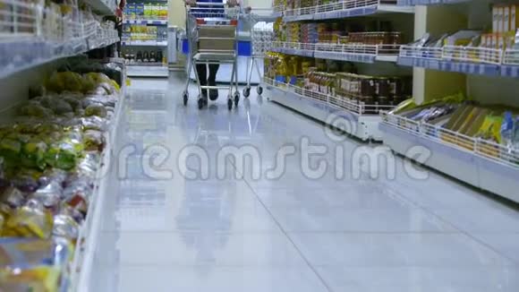 女孩超市的员工用不同的产品在货架上滚动一辆手推车视频的预览图