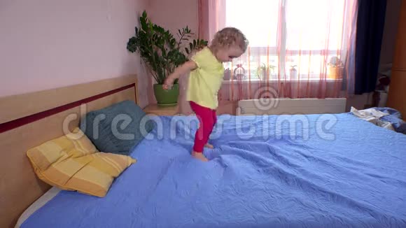 嬉戏的小女孩在卧室的床上蹦蹦跳跳地跑视频的预览图