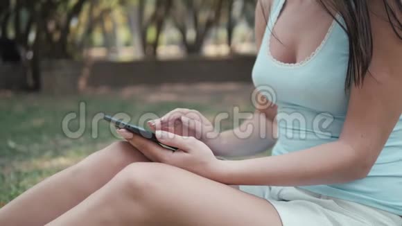 利用平板电脑网上购物理念年轻美丽的女孩坐在公园的草坪上视频的预览图