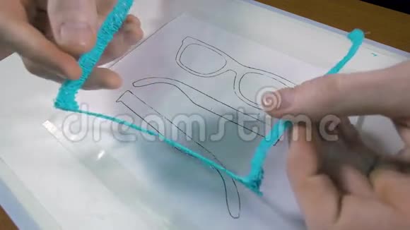 男人展示了用3D打印笔制作的眼镜视频的预览图