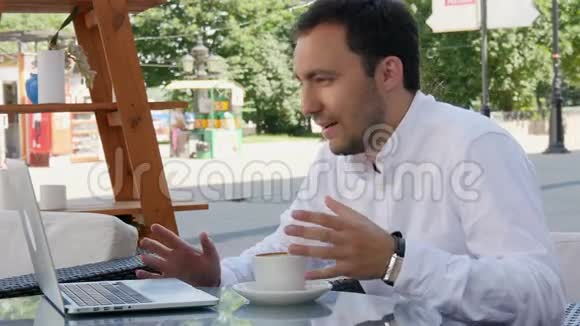 男人在咖啡馆里用Skype和朋友交流用笔记本电脑和咖啡视频的预览图