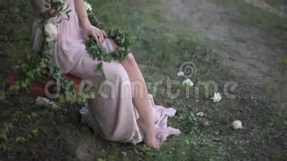 年轻女子穿着轻薄的紧身衣嬉戏地露出腿坐在装饰着鲜花的秋千上视频的预览图