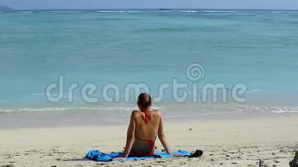 一个女孩坐在美丽的海滩上视频的预览图