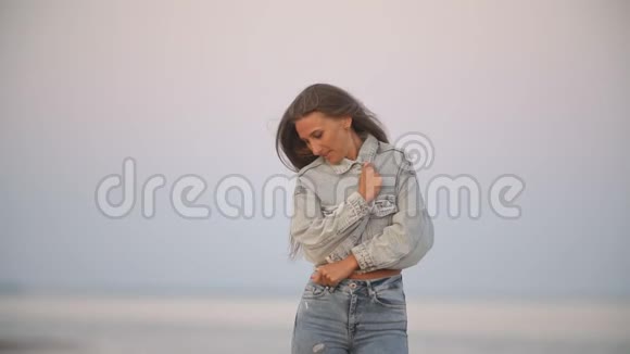 穿牛仔裤的女孩在大海的背景下视频的预览图