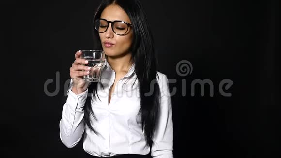 女商人拿着一杯水和饮料被隔离在黑色背景上视频的预览图