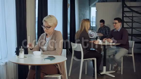 年轻漂亮的女人坐在桌子旁在室内喝咖啡视频的预览图