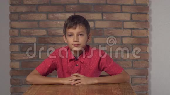 坐在办公桌前的孩子拿着一张挂图背景红砖墙上有刻字的工作人员视频的预览图