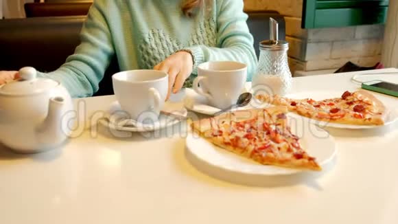 在餐馆里吃披萨喝茶的年轻美女视频的预览图