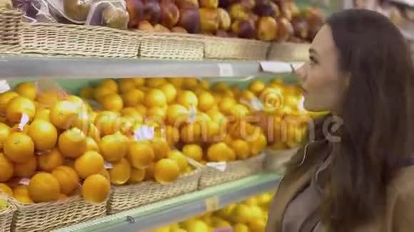迷人的女孩来到展示水果和采摘橘子和猕猴桃视频的预览图