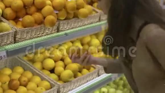 可爱的女孩在超市里选择新鲜的柑橘类水果视频的预览图
