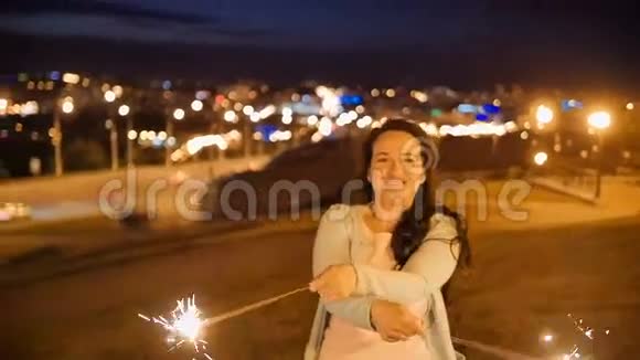 微笑的年轻女子站在高高的山上背景是城市夜景视频的预览图