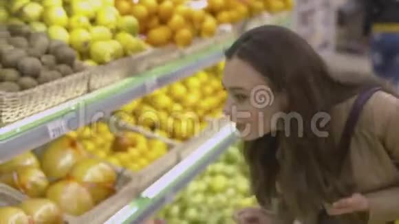 可爱的女孩站在超市的货架旁拿着水果视频的预览图