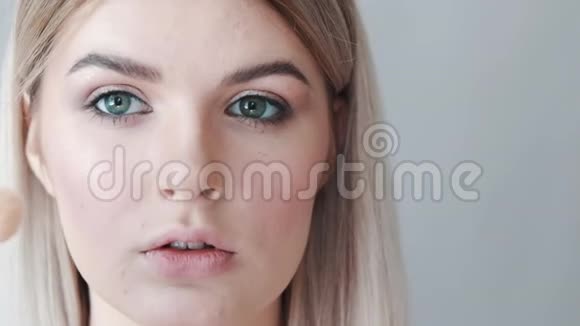 化妆年轻漂亮的女孩用刷子在脸颊上化妆视频的预览图