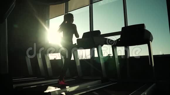 跑步机上的心脏减肥的练习跑步机上女孩的剪影年轻的运动女孩视频的预览图