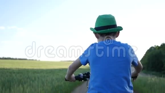 男孩骑自行车在野外慢动作后视视频的预览图