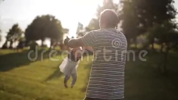 年轻快乐的爸爸在日落时分把他的小女儿关在公园里视频的预览图