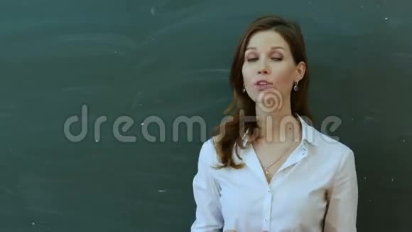 年轻快乐的女老师站在绿色的木板上说话视频的预览图