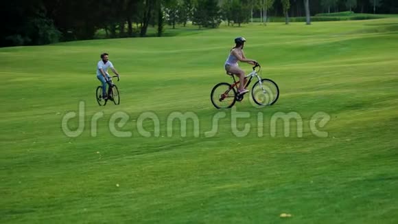 年轻人在绿色草坪上骑自行车视频的预览图