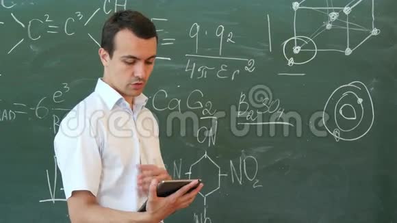 化学老师从站在黑板前的平板电脑上领导讲座视频的预览图